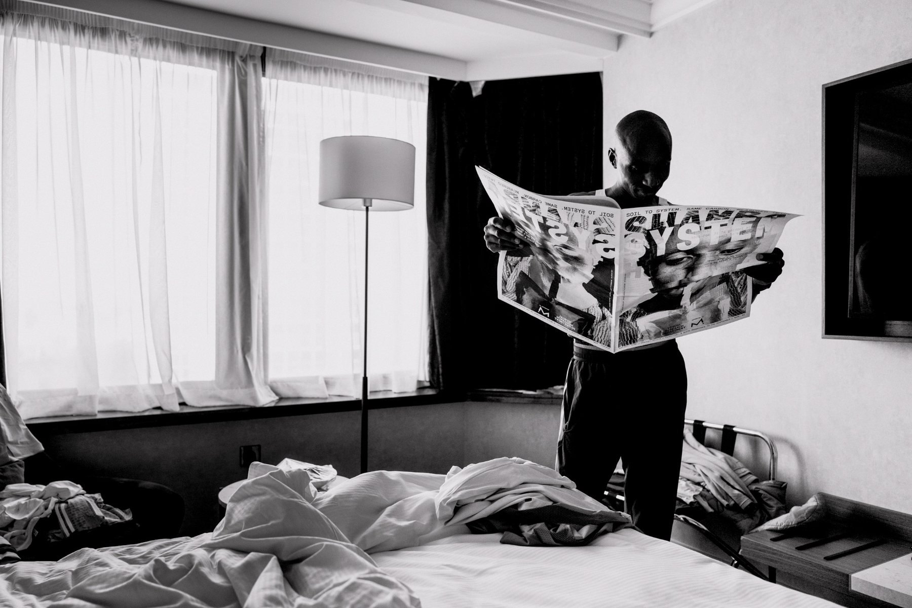 Sabastian Sawe reading the Shamba System newspaper in a hotel room.